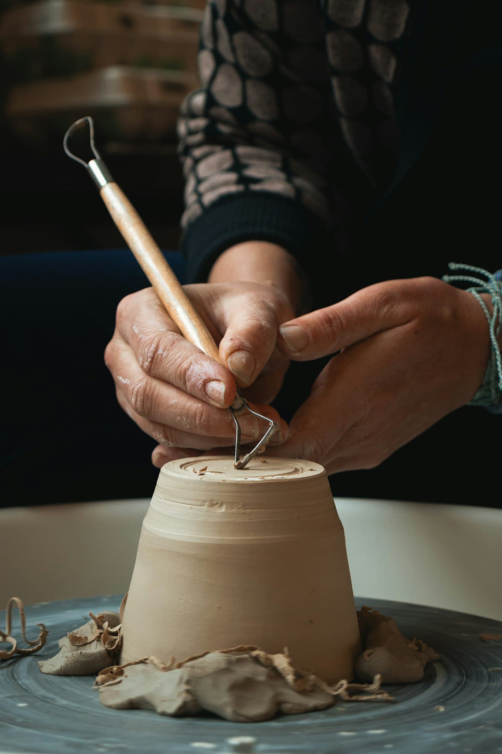 A hand holding a small cup of a thick, creamy white drink — buttermilk or lassi served at the household table.